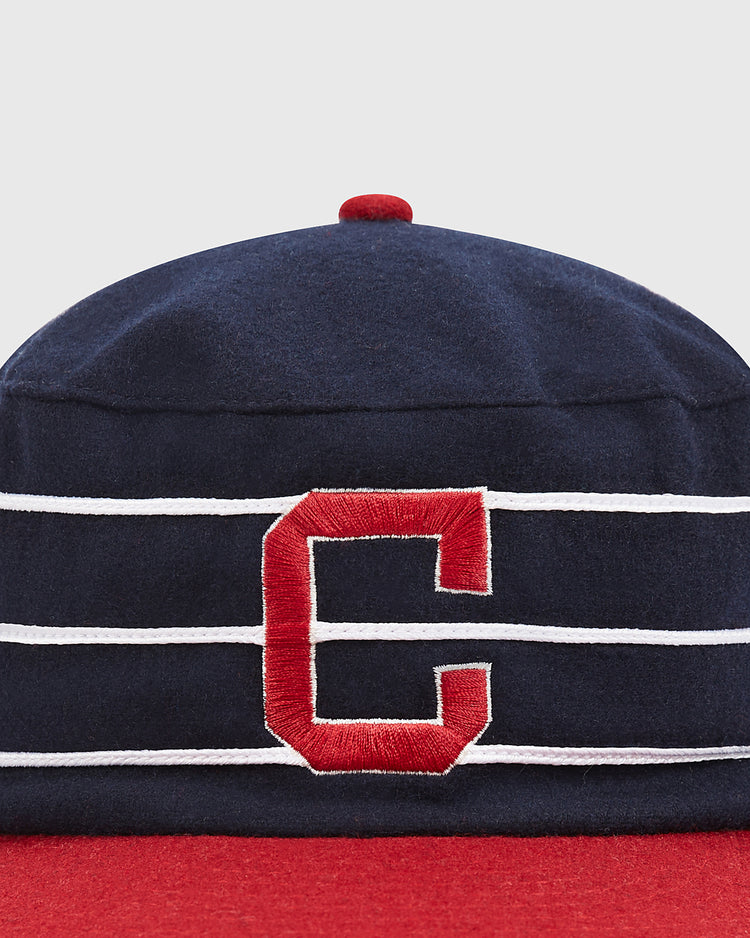 The Ebbets Field Charleston Charlies Pillbox Cap is a retro-inspired baseball hat in navy blue, featuring three white horizontal stripes, a prominent red “C” on the front, and finished with a bold red brim and top button.