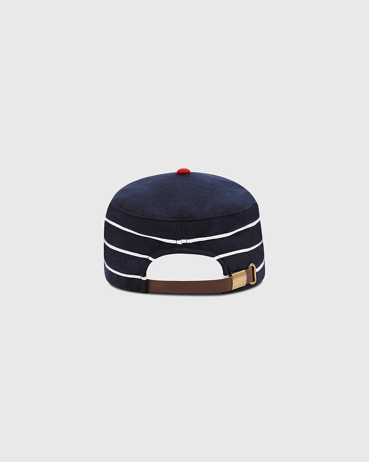 The Ebbets Field Charleston Charlies Pillbox Cap is shown from the back against a plain gray background, displaying its retro navy blue design with white stripes, a red top button, and a brown adjustable strap with a brass buckle.