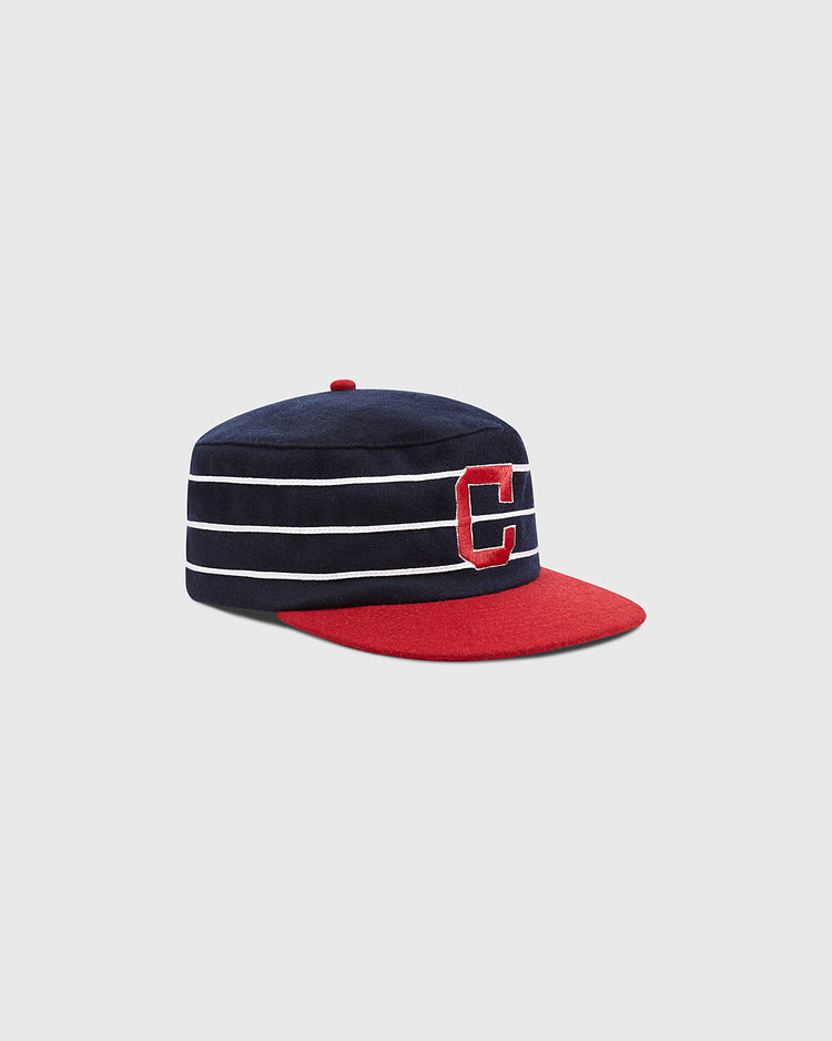 The Charleston Charlies Pillbox Cap by Ebbets Field is a retro-style baseball cap in navy blue with white horizontal stripes, featuring a red brim and a large red letter “C” on the front.