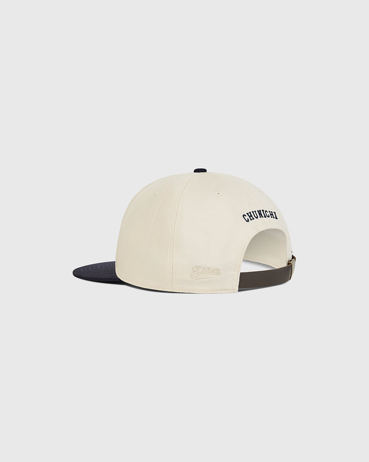 The Chunichi Dragons Cotton Twill Ballcap by Ebbets Field features a cream-colored cotton twill crown, a black brim, and an adjustable strap. “CHUICHU” is embroidered on the back in tribute to the legendary Chunichi Dragons ballcaps from the Central League championship era. The cap is photographed against a plain, light background.