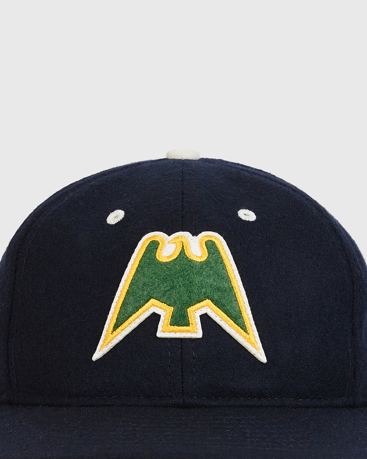 The Nankai Hawks 1950 Authentic Wool Ballcap by Ebbets Field is a navy blue wool cap with a green and yellow bird-inspired logo embroidered on the front, drawing inspiration from Japanese baseball’s 1950 Nankai Hawks. The cap is displayed against a plain light background.