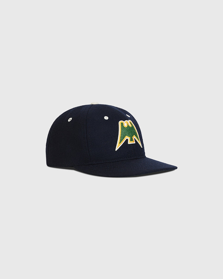 The Ebbets Field Nankai Hawks 1950 Authentic Wool Ballcap is a navy blue cap with a green and yellow stylized M logo on the front, inspired by classic Japanese baseball, shown against a plain light gray background.