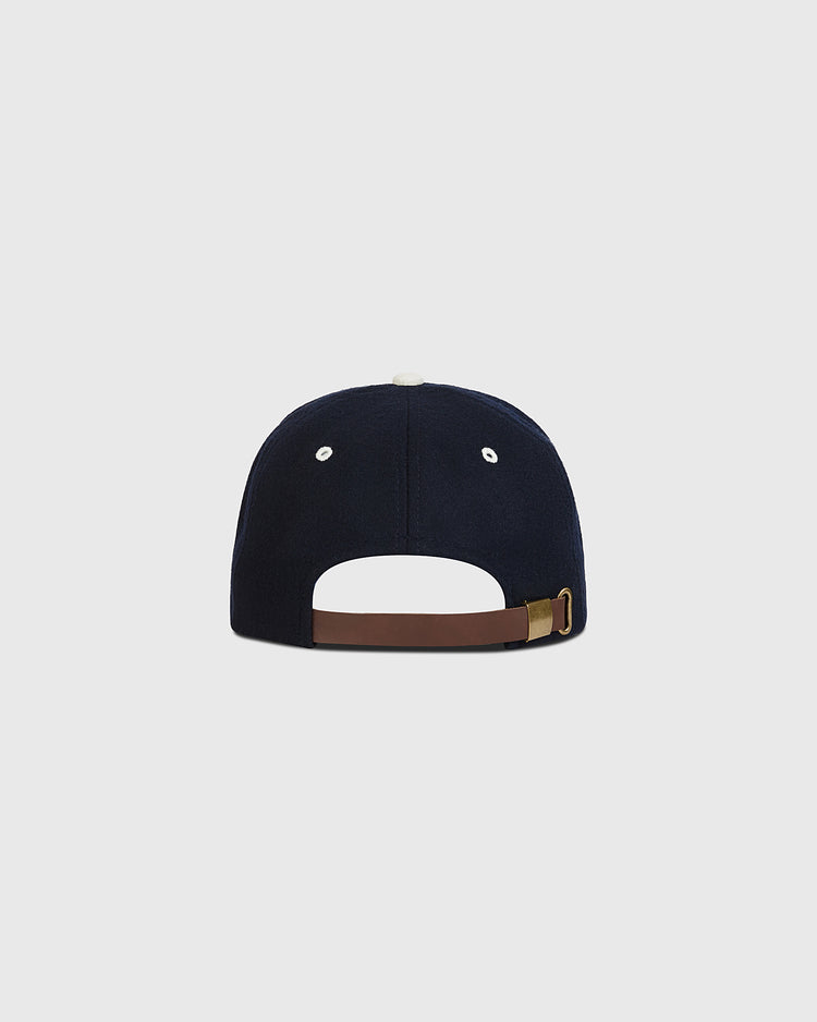 An authentic navy blue wool ballcap by Ebbets Field, inspired by the 1950 Nankai Hawks, viewed from the back and featuring a brown adjustable strap with a gold buckle, plus white stitching around the top button and eyelets in classic Japanese baseball style.