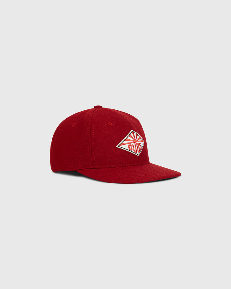 The Taiyo Cubs 1928 Authentic Wool Ballcap by Ebbets Field is a red baseball cap with a flat brim, featuring a white and red diamond-shaped CLUB patch on the front. The cap is displayed against a plain light gray background.