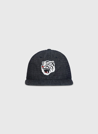 The Ebbets Field Osaka Tigers Japanese Indigo Cotton Dobby Ballcap is a dark, textured indigo-dyed cap featuring a white embroidered tiger head with black stripes and red accents on the front. Inspired by Japanese baseball and echoing the iconic Osaka Tigers, this ballcap is showcased against a plain light gray background.