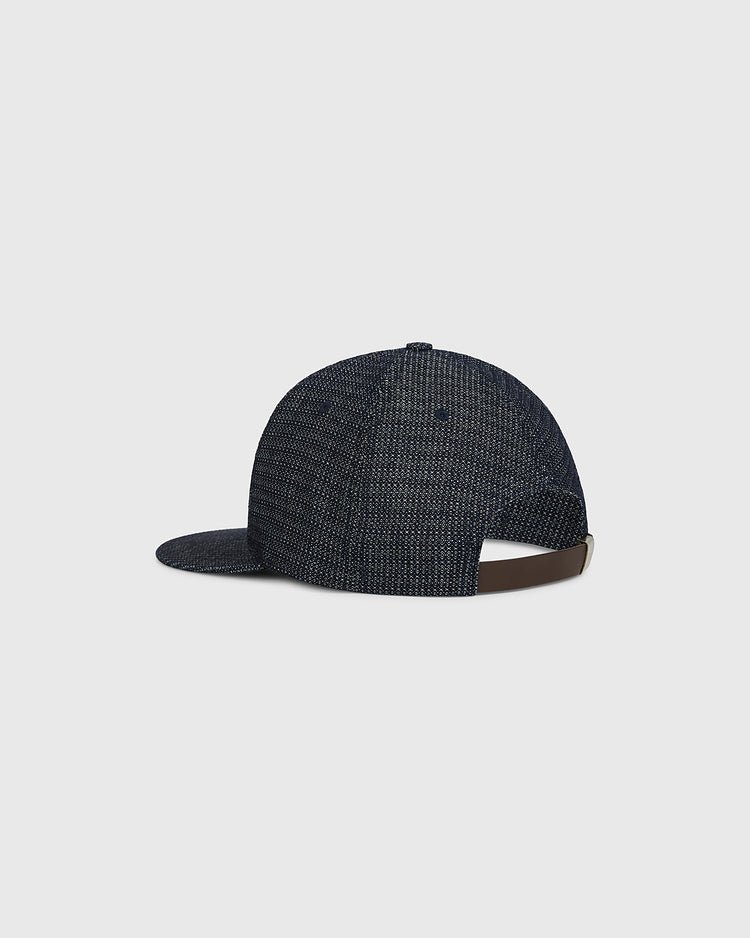 The Ebbets Field Osaka Tigers Japanese Indigo Cotton Dobby Ballcap is featured from the back, displaying its indigo-dyed dobby cotton fabric, curved brim, and an adjustable brown strap with a metal clasp. Inspired by Japanese baseball style and the legendary Osaka Tigers, this cap appears against a plain light gray background.