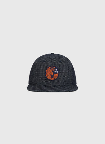 The Ebbets Field Hiroshima Carp Japanese Indigo Cotton Dobby Ballcap, crafted from premium Japanese cotton and dyed a deep indigo blue, showcases an orange embroidered fish with water bubbles on the front, set against a plain light gray background.