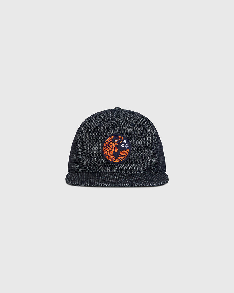 The Ebbets Field Hiroshima Carp Japanese Indigo Cotton Dobby Ballcap, crafted from premium Japanese cotton and dyed a deep indigo blue, showcases an orange embroidered fish with water bubbles on the front, set against a plain light gray background.