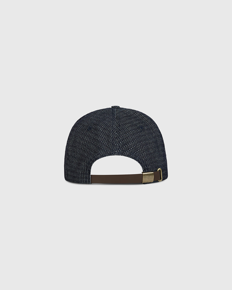 The Sankei Atoms Japanese Indigo Cotton Dobby Ballcap by Ebbets Field is displayed from the back, highlighting its adjustable brown leather strap with a brass buckle. The cap’s deep indigo hue and textured cotton dobby fabric reflect classic Japanese baseball heritage, set against a plain light gray background.