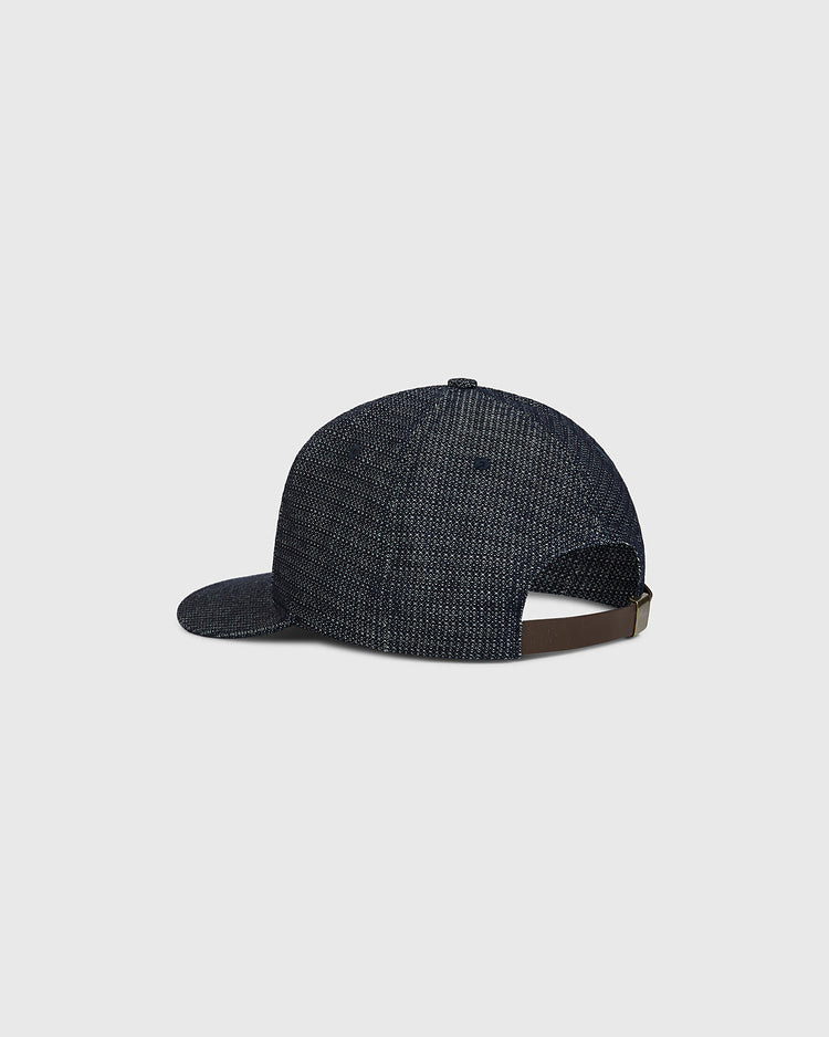 An Ebbets Field Tokyo Giants 1940 Japanese Indigo Cotton Ballcap is displayed from the back, showcasing its textured dark blue fabric and an adjustable brown strap with a metal buckle. The background is plain light gray.