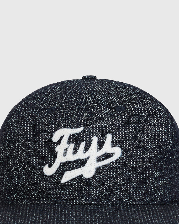 A close-up of the Ebbets Field Fuji Athletic Club Japanese Indigo Cotton Dobby Ballcap, showcasing its deep indigo textured cotton finish and white “Fuy” script on the front, set against a plain light background—an accessory inspired by classic Japanese American baseball heritage and the legacy of the Fuji Athletic Club.