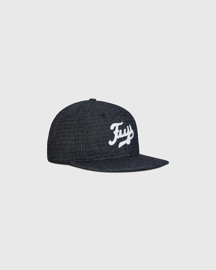 The Ebbets Field Fuji Athletic Club Japanese Indigo Cotton Dobby Ballcap is a dark, textured snapback hat featuring a flat brim and the word “Fry” in white script across the front panel. Inspired by classic indigo-dyed ballcap styles once worn by Japanese American baseball teams like the Fuji Athletic Club, it is showcased against a plain light gray background.