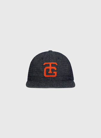 An Ebbets Field Tokyo Giants 1953 Japanese Indigo Cotton Dobby Ballcap, featuring a textured dark blue design and a bold red embroidered TG logo on the front, is displayed against a plain light gray background.
