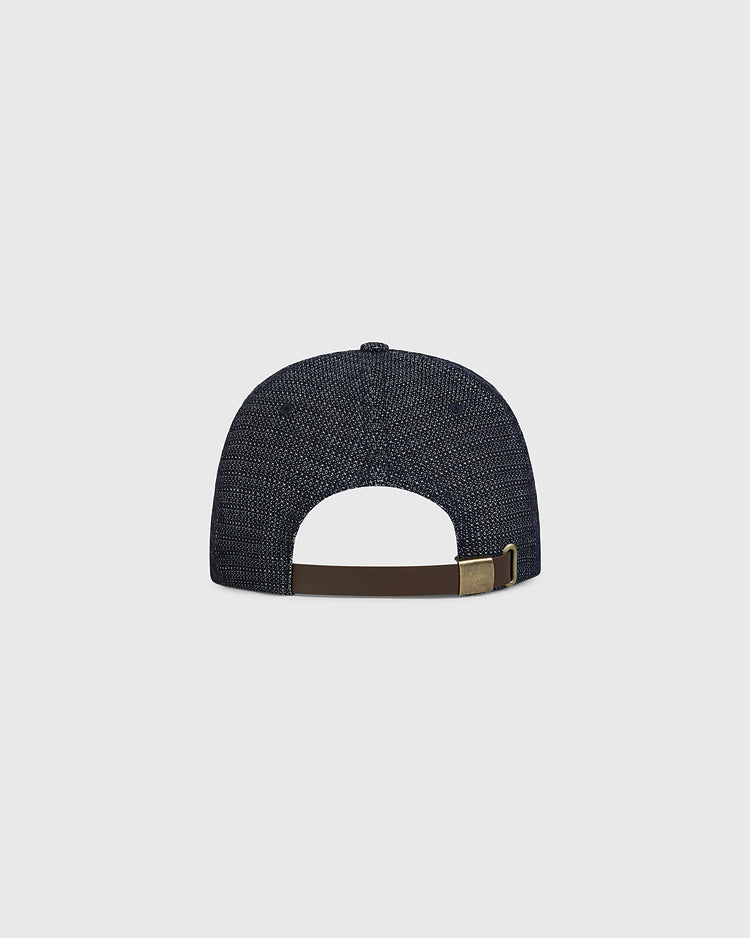 The Ebbets Field Tokyo Giants 1953 Japanese Indigo Cotton Dobby Ballcap is shown from the back, highlighting its dark blue textured fabric and a brown adjustable strap with a brass buckle, set against a plain light gray background.