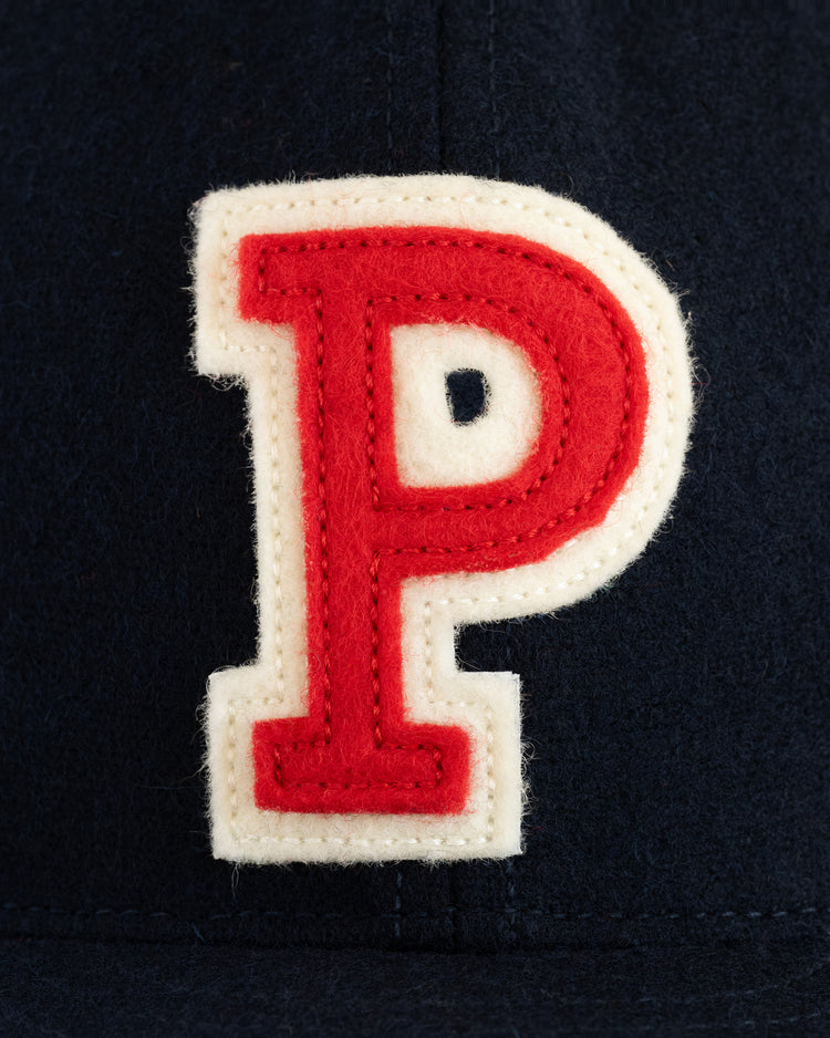 A close-up of a red letter P with a white border, sewn onto dark fabric from the EFF University of Pennsylvania 1958 Authentic Wool Ballcap.
