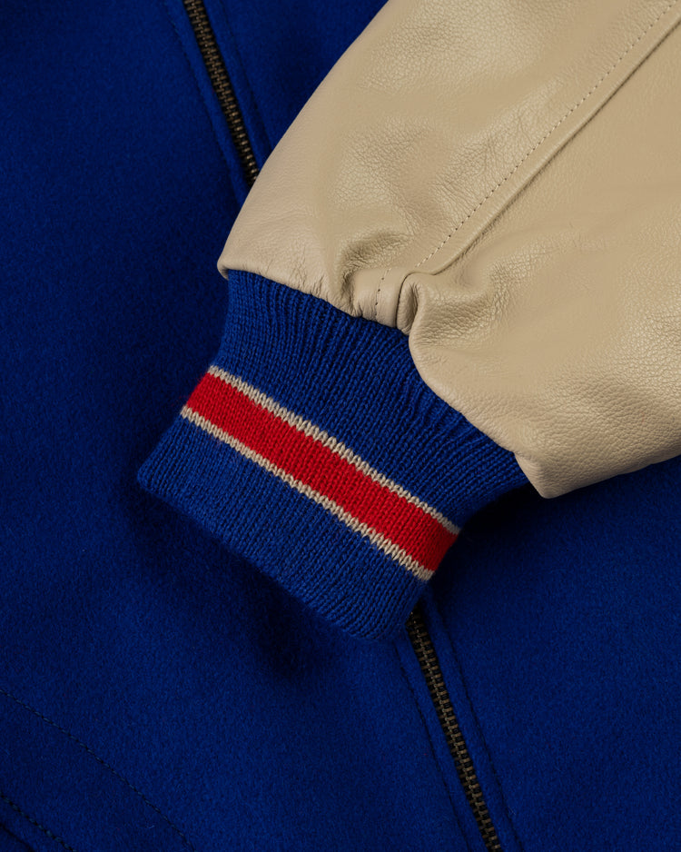 Close-up of the EFF Pittsburgh Pirates 1945 Authentic Wool & Leather Varsity Jacket sleeve, featuring a beige leather arm and a blue cuff with red and white stripes, set against the royal blue jacket body with visible zipper.