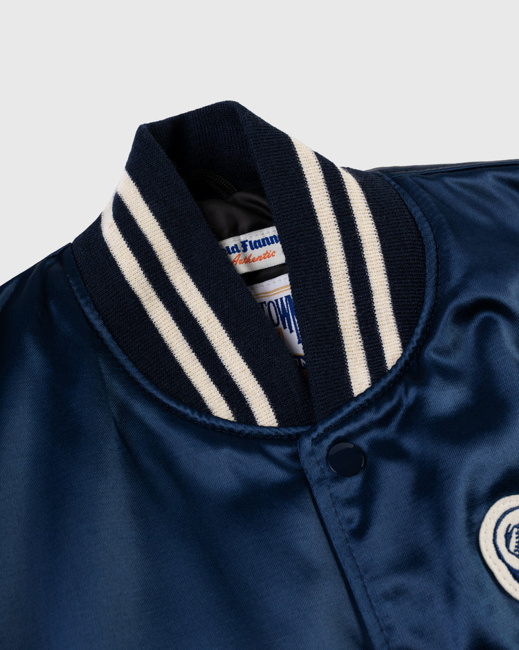 Close-up of the collar and upper chest of the EFF Philadelphia Athletics 1953 Authentic All Satin Varsity Jacket in navy blue with white and navy striped ribbed trim, visible snap button, partial elephant patch, and inside label.