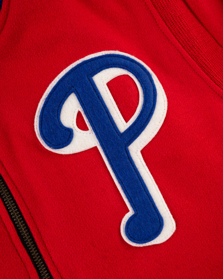 Close-up of red wool fabric on the EFF Philadelphia Phillies 1949 Authentic All Wool Varsity Jacket, featuring an embroidered blue and white P logo and a partially visible black zipper on the left.