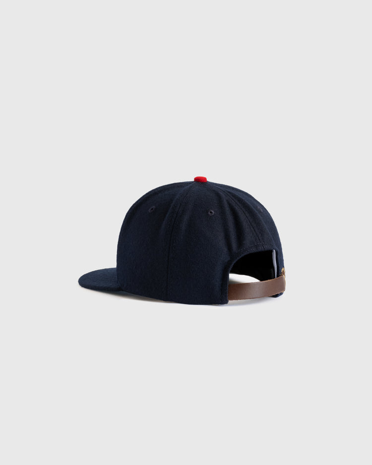 The EFF Minneapolis Millers 1938 Authentic Wool Ballcap in navy blue is shown from the back, with a brown adjustable strap and red top button against a light gray backdrop—a faithful reproduction of the classic cap.