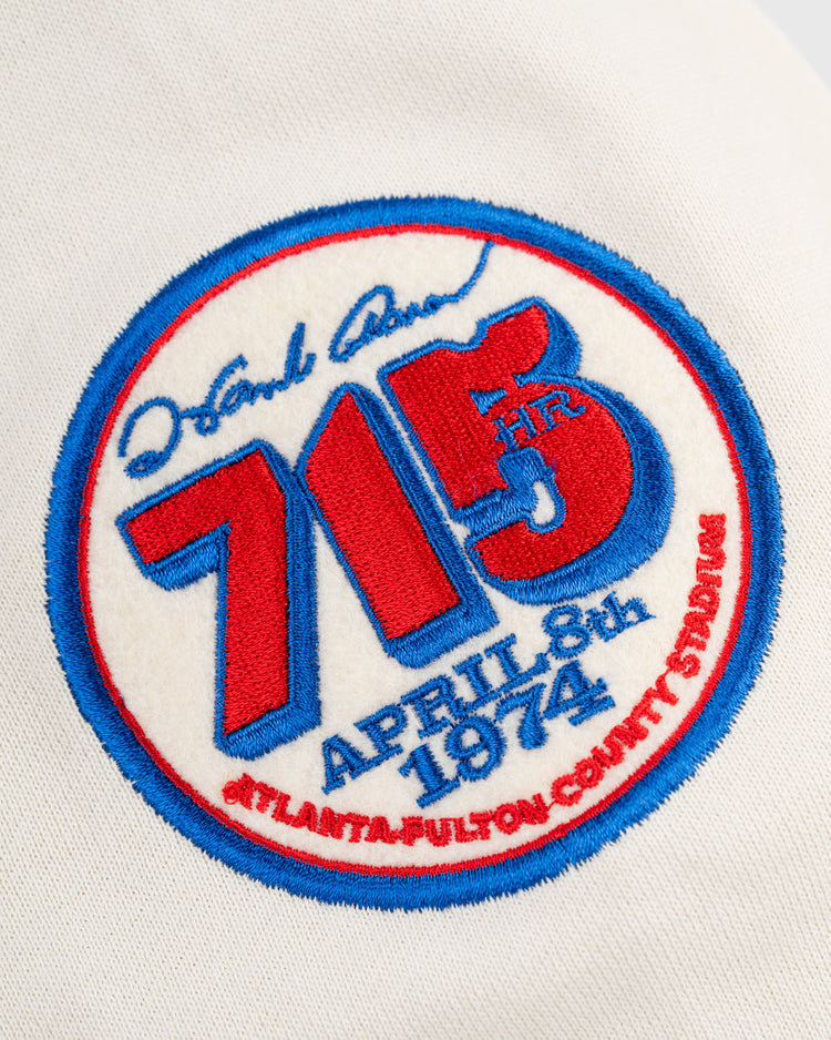 The Hank Aaron French Terry Script Hooded Sweatshirt by EFF honors Aaron’s legendary 715th home run on April 8, 1974, surpassing Babe Ruth’s record, featuring “Atlanta-Fulton County Stadium” in red script.