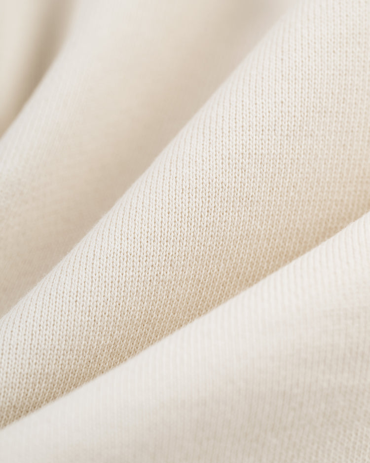 Close-up of cream-colored, soft French terry fabric with fine knit texture and gentle folds, reflecting the vintage charm and cozy style of the EFF Hank Aaron Script Hooded Sweatshirt.