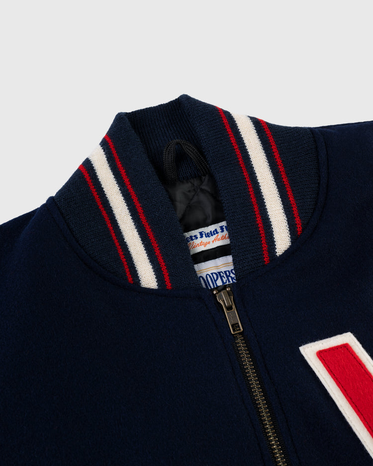 Close-up of the EFF Washington Senators (Nationals) 1951 Authentic All Wool Varsity Jacket in navy, featuring a red, white, and blue striped ribbed collar, a large white “V” on the right side, and a partly open zipper showing the inner label.