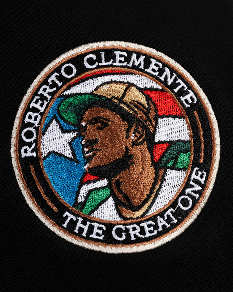 The EFF Roberto Clemente French Terry Feld Pullover Hoodie features an embroidered patch displaying Clemente in a Pirates cap, set against a colorful background with ROBERTO CLEMENTE THE GREAT ONE around the edge.