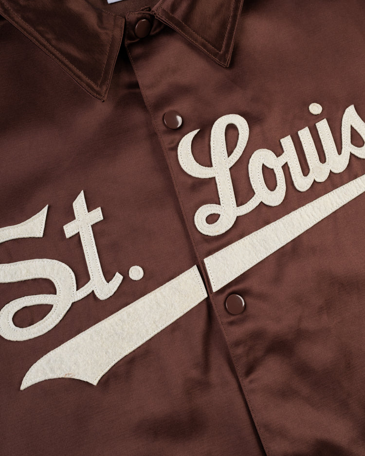 A close-up of the EFF St. Louis Browns 1952 Satin Windbreaker Jacket in brown, featuring cream textured St. Louis script with an underline and snap buttons, inspired by classic MLB vintage windbreakers.