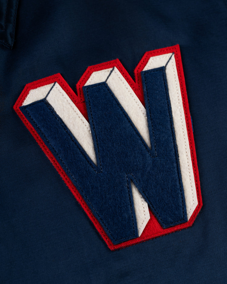 A large, 3D-style navy, white, and red “W” patch is sewn on dark blue fabric, adding vintage flair to the EFF Washington Senators 1959 Satin Windbreaker Jacket.