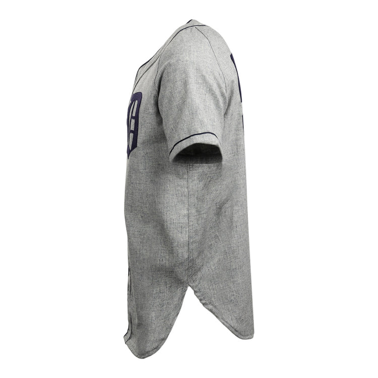 Side view of the EFF Duke University 1953 Road Jersey, a gray short-sleeve button-up with dark blue trim, partial numbers on front and back, curved hem, and textured fabric, inspired by the College Vault baseball jersey.