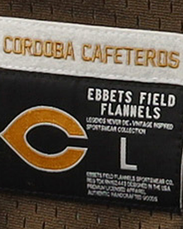 A close-up of the EFF label on the Cordoba Cafeteros EFF DNA Replica V-Neck Mesh Jersey, with a large L size tag sewn onto brown fabric, highlights the team’s legacy in Mexican baseball history.