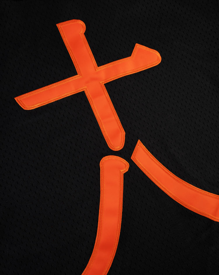 Close-up of orange Chinese characters stitched on black mesh fabric from the EFF Tokyo Giants Mesh V-Neck Baseball Jersey, showing vintage-inspired details and visible texture.