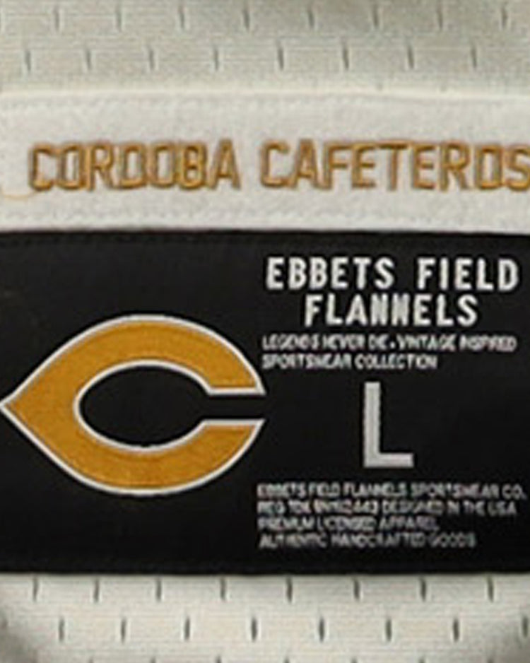 The EFF Cordoba Cafeteros EFF DNA Replica Button-Up Mesh Jersey features a gold CORDOBA CAFETEROS label on white, inspired by Mexican pro baseball, and a patch with a yellow C, “EBBETS FIELD FLANNELS,” size L, and product info in white on black.