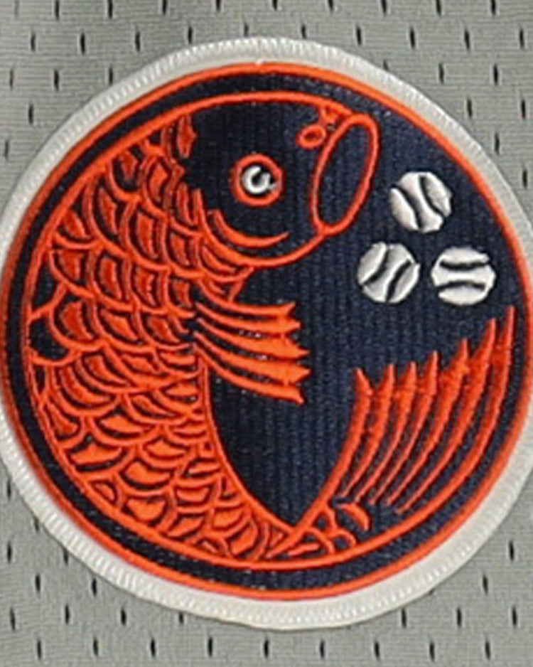 The Hiroshima Carp EFF DNA Replica Button-Up Mesh Jersey by EFF features a circular patch with an orange fish and three white baseballs on a dark blue background, sewn onto light gray perforated vintage mesh fabric.