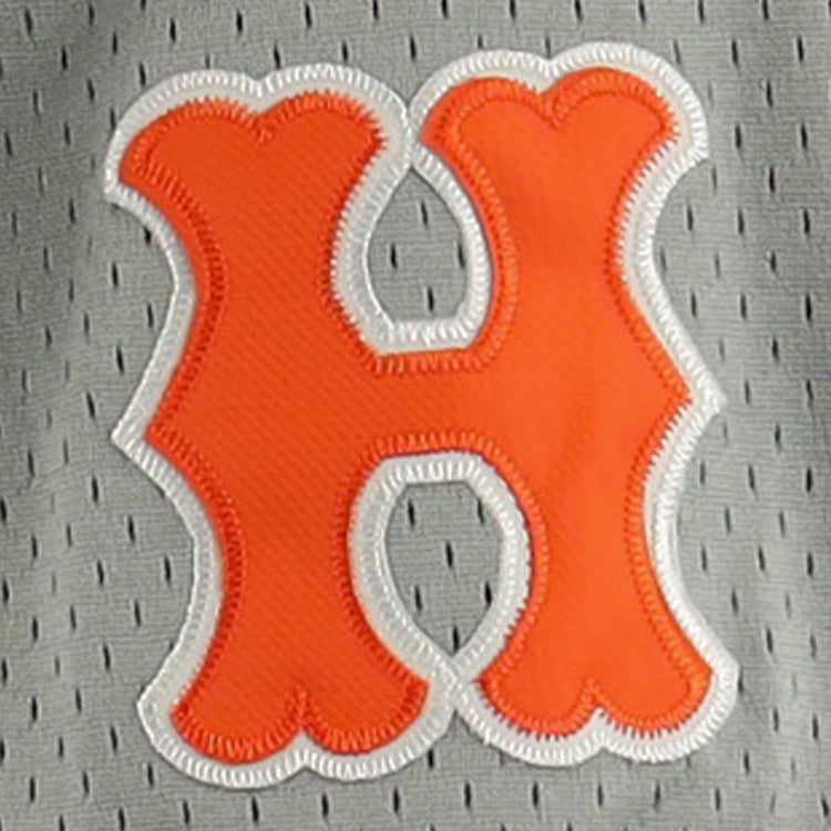 An orange, rounded letter H with a white embroidered border is sewn onto the gray mesh of the EFF Hiroshima Carp DNA Replica Button-Up Mesh Jersey, echoing vintage Japanese Central League styles.