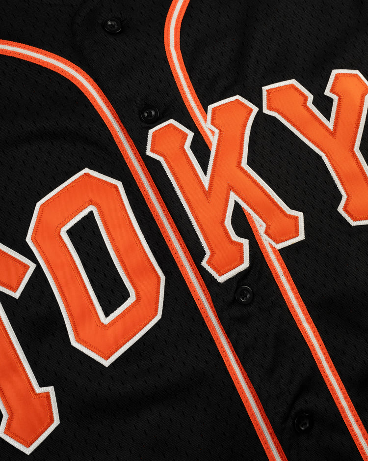 Close-up of the EFF Tokyo Giants Mesh Button-Up Jersey, a vintage-inspired black mesh design with orange and white trim, featuring bold orange TOKYO lettering outlined in white—echoing classic Tokyo Giants style.