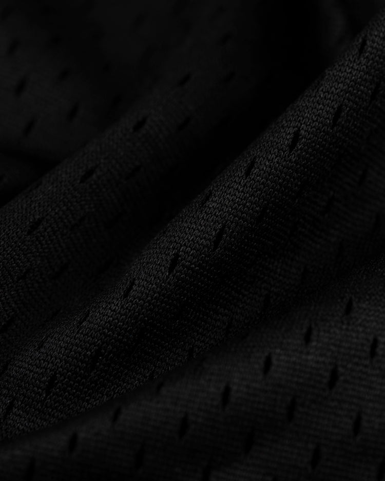 Close-up of black mesh fabric with small perforations and soft folds from the EFF Tokyo Giants Mesh Button-Up Jersey, capturing a vintage-inspired look and depth.