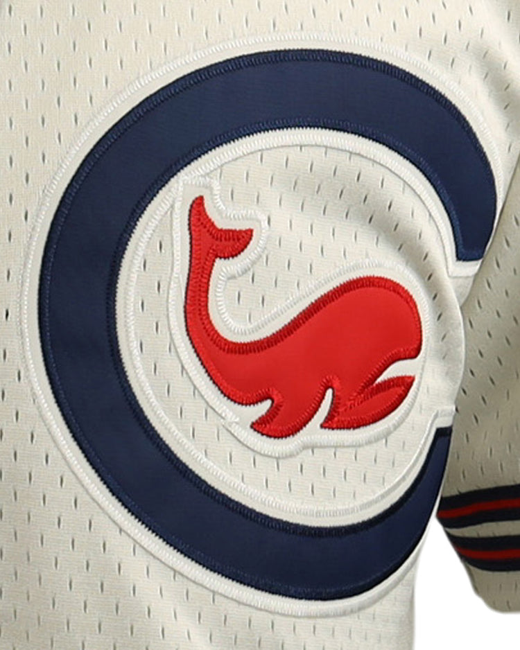 Close-up of the EFF Chicago Whales DNA Replica Button-Up Mesh Jersey, cream-colored with a blue “C” and red cartoon whale logo outlined in white and blue, plus thin vertical perforations and red-blue sleeve stripes.
