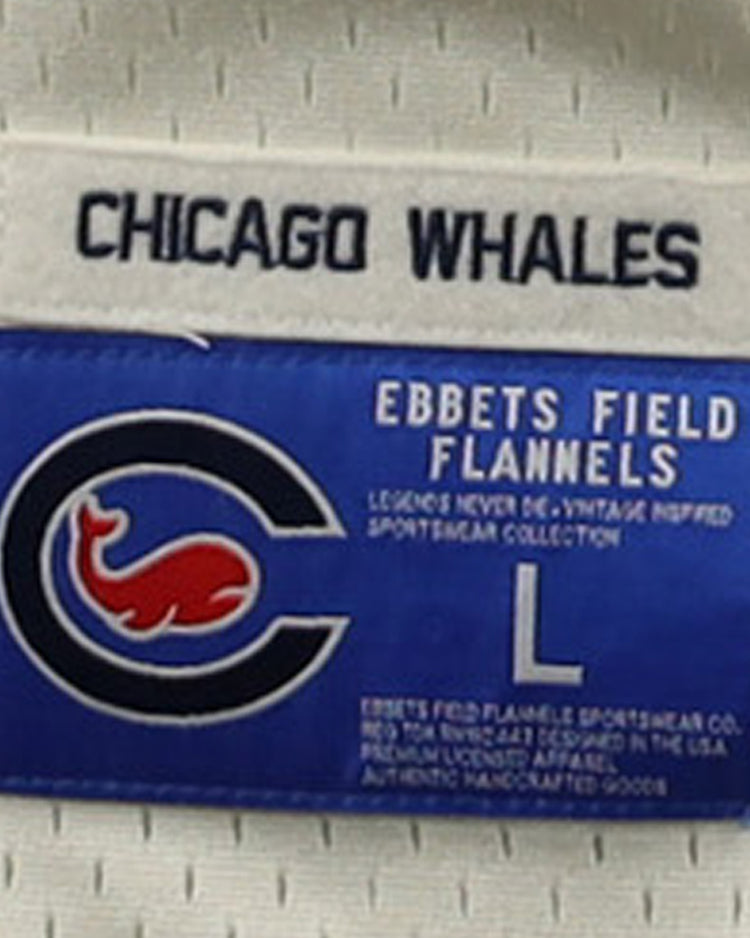 A label for the EFF Chicago Whales DNA Replica Button-Up Mesh Jersey features CHICAGO WHALES on top, a blue patch with a red whale inside a C—honoring the Federal League team—and text: EBBETS FIELD FLANNELS, size L.