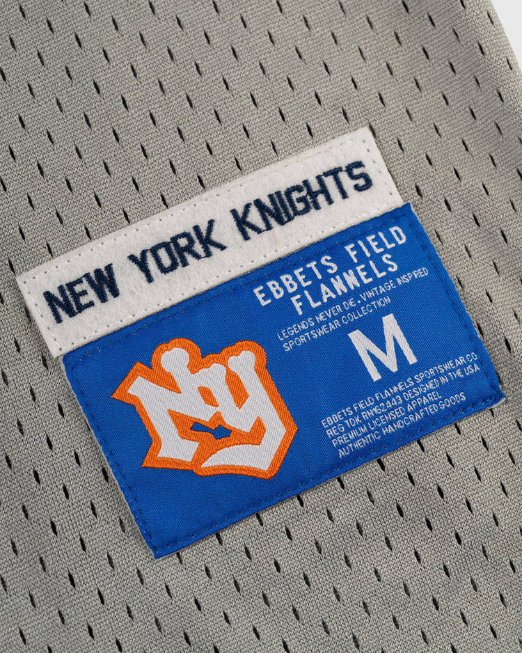 Close-up of the gray New York Knights Mesh Button-Up Baseball Jersey by EFF, featuring the team patch, blue label with orange M for medium, and sportswear collection details.