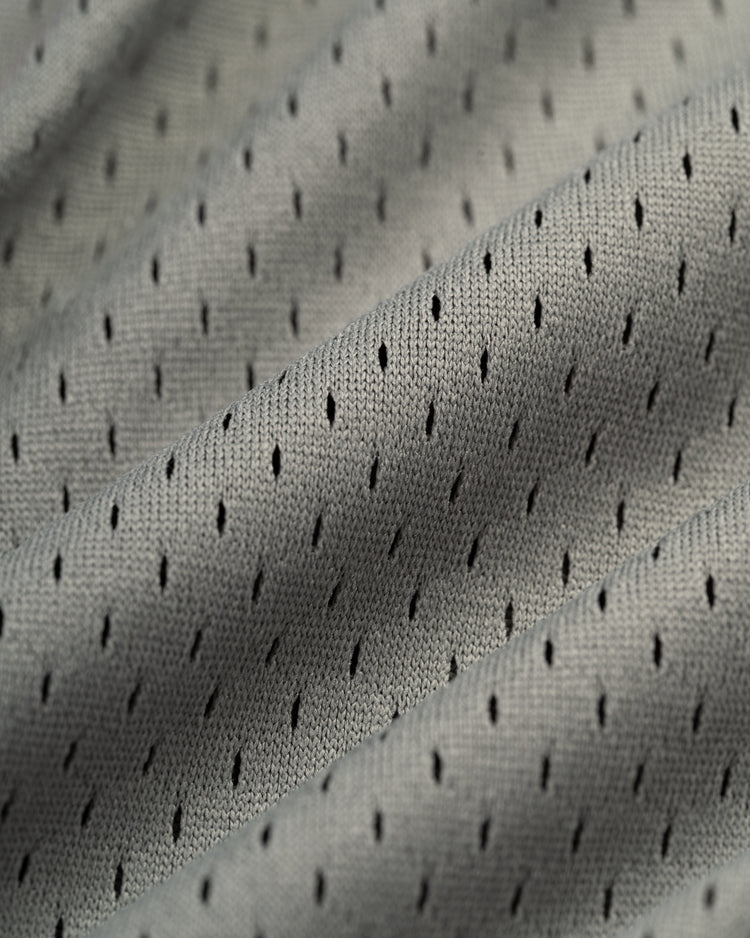 Close-up of light gray, textured mesh fabric with black dots and diagonal folds on the EFF New York Knights Mesh Button-Up Baseball Jersey—soft, breathable, and perfect for athletic or casual wear, evoking vintage baseball style.