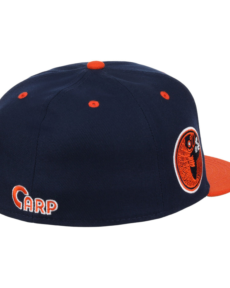 The EFF Hiroshima Carp EFF DNA Fitted Ballcap is navy blue with orange accents, an orange brim and button, a circular fish logo on the side, CARP embroidered on the back, in classic Ebbets Field Flannels style.