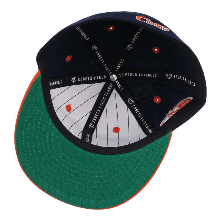 The Hiroshima Carp EFF DNA Fitted Ballcap by EFF is a navy blue vintage cap with a green underbrim, orange stitching on the brim, inner pinstripes, and “EBBETS FIELD FLANNELS” text on black inner bands.