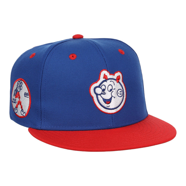 The EFF Reddy Kilowatt EFF DNA Fitted Ballcap features a blue vintage design with a red brim, cartoon bear face front, and side patch of a bear playing baseball—classic style inspired by Ebbets Field Flannels.