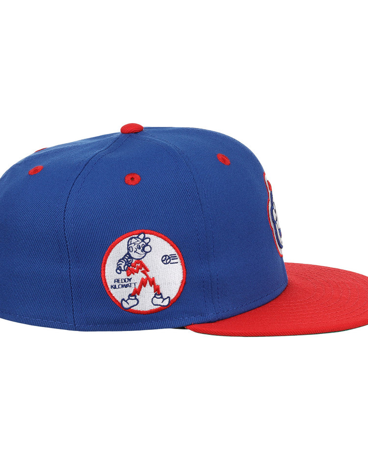 The EFF Reddy Kilowatt EFF DNA Fitted Ballcap features a blue crown, red brim, and an embroidered cartoon bear holding a bat in a red oval patch on the side, inspired by classic Ebbets Field Flannels style.