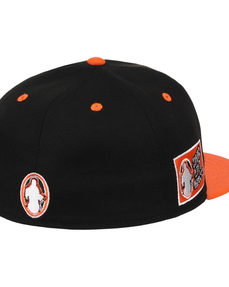 The EFF Sioux City Ghosts DNA Fitted Ballcap is a black vintage-inspired cap with orange accents, multiple patches including the teams logo, orange eyelets, and a flat orange brim, shown from the back and side.
