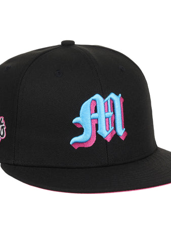 The EFF Miami Giants NLB Team Color Fitted Ballcap is a vintage-inspired black cap with a bold blue and pink M on the front and a matching embroidered San Francisco Giants team logo patch on the side.