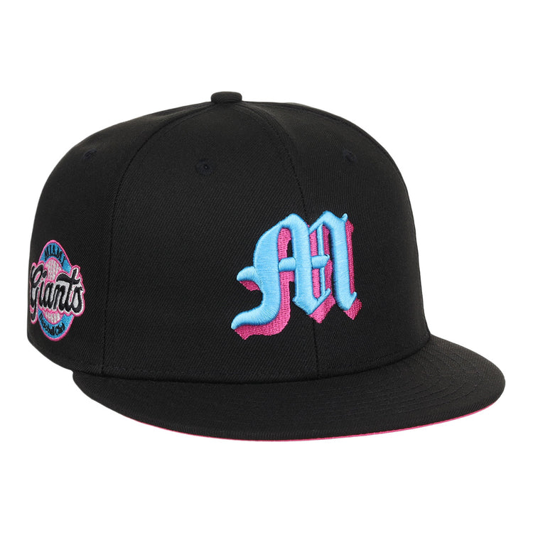 The EFF Miami Giants NLB Team Color Fitted Ballcap is a vintage-inspired black cap with a bold blue and pink M on the front and a matching embroidered San Francisco Giants team logo patch on the side.