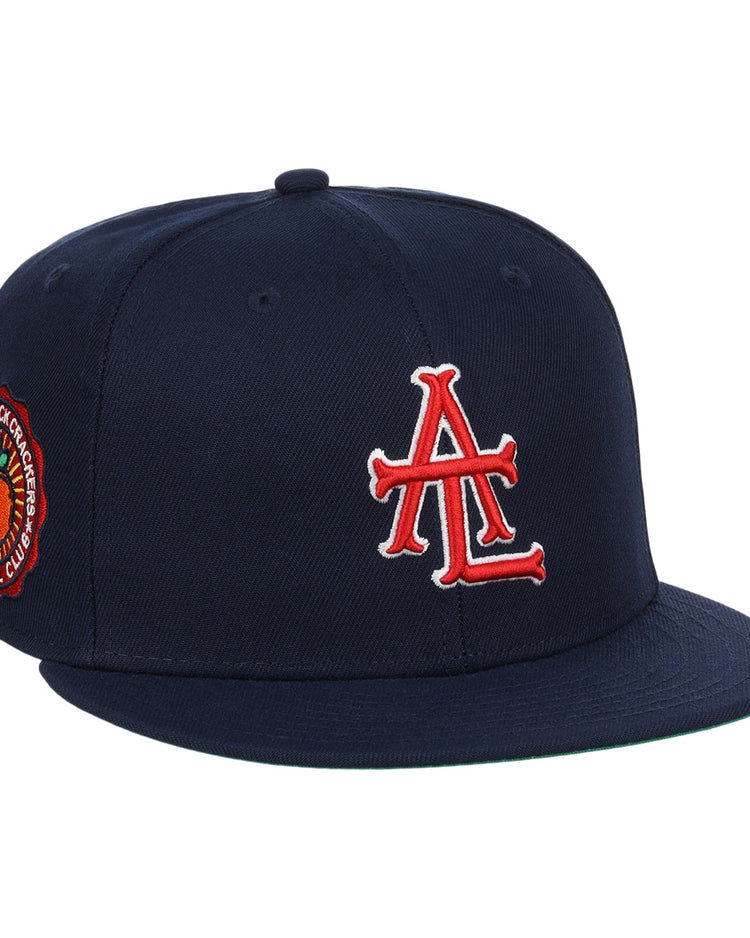The EFF Atlanta Black Crackers NLB Team Color Fitted Ballcap is a vintage-inspired navy hat featuring a bold red and white logo on the front and an orange-and-black round patch on the side.