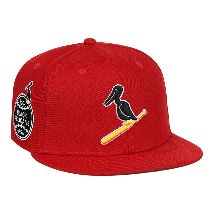 The EFF New Orleans Black Pelicans NLB Team Color Fitted Ballcap in red features a black pelican on a yellow bat, a side patch with New Orleans Black Pelicans 1922, and honors the Negro Southern League with an added small pelican graphic.